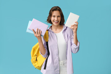 Wall Mural - Beautiful female student with backpack and books on blue background