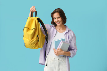 Wall Mural - Beautiful female student with backpack and books on blue background