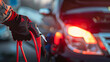 © john - Man holding red and black battery cable for charging the car. Car Repair and maintenance concept