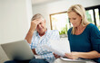© Jadon Bester/peopleimages.com - Mature, couple and home with laptop or documents, stressed man and woman planning for financial expenses. Bills, paperwork and online for tax review or budget, insurance contact and sofa in lounge