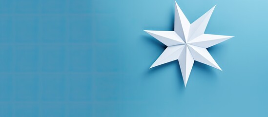 Wall Mural - origami star made of blue paper placed on a white background with copy space image.