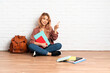 © luismolinero - Teenager student woman with pink hair sitting on the floor at indoors pointing finger to the laterals and happy
