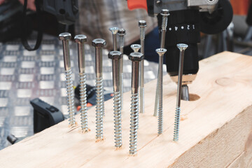 Poster - A pile of screws are on a wooden surface. The screws are of different sizes and shapes. Concept of organization and order, as the screws are neatly arranged in rows