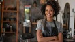 © Salsabila Ariadina - Portrait of a confident young african american female hairdresser in an apron standing next to a salon chair