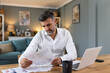 © Graphicroyalty - Handsome man freelancer noting information for planning project doing remote job via laptop computer. Man reading email on modern laptop device .