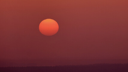 Wall Mural - The sun sets in the mysterious haze of the evening red sky