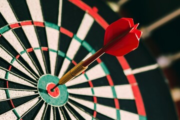 Dart in bulls eye of dartboard with shallow depth of field concept for hitting target