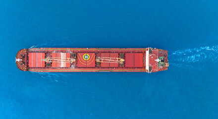 Wall Mural - A bulk carrier freight ship at traveling on full motion over blue sea . Aerial view drone photo