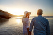 © peopleimages.com - Mature, happy couple and walking with love on beach in sunset for support or bonding in nature. Back view of man, woman or lovers enjoying romance, outdoor holiday or summer by water or ocean coast