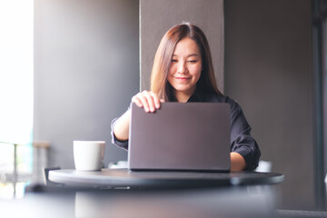 Wall Mural - portrait image of a woman opening or closing laptop computer, getting ready for work, finished work 