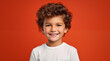 © David Giraud - Un petit garçon heureux et souriant, âgé de 5 ans, cheveux bruns, portant un tee-shirt blanc, arrière-plan isolé, coloré, rouge.
