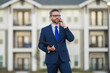 © Volodymyr - Real estate agent business man in suit hold holder clipboards and talking on phone. Businessman. Business Man broker or real estate agent. Business man in suit outdoor. Real estate business man.