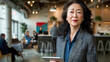 © Валерія Дємідова - a beautiful middle-aged asian woman in a suit stands in the office, holding a tablet in her hands