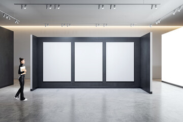 Leinwandbilder - A person standing in a gallery with three empty frames on a wall, modern spacious interior design