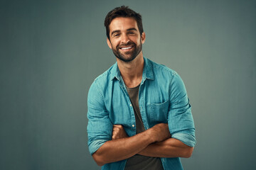 Wall Mural - Arms crossed, fashion and happy with portrait of man in studio on gray background for relaxed clothing style. Casual, confident and natural with smile of person in outfit to model clothes or shirt