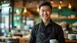 © MiguelAngel - Portrait of a smiling Asian waiter, wearing an apron, inside a restaurant.
