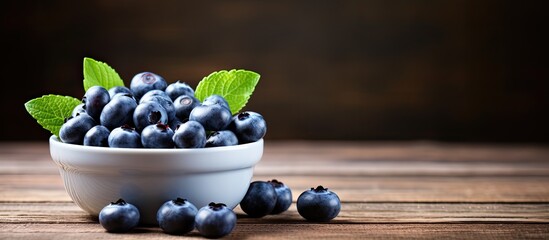 Poster - Close up image of fresh blueberries in a small bowl on a wooden table with copy space image.