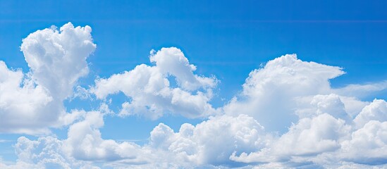Poster - Background of blue sky with fluffy white clouds providing copy space image.