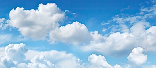 Poster - Background of a clear blue sky dotted with small fluffy clouds offers ample copy space image.
