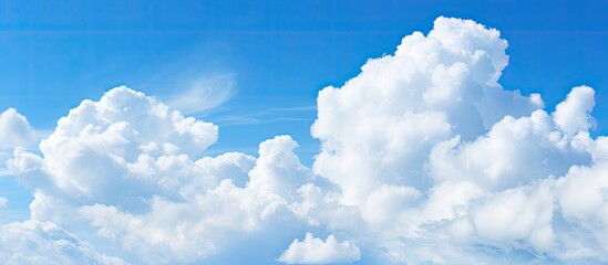 Poster - Blue sky with fluffy white clouds on a sunny day, creating a serene atmosphere for a copy space image.