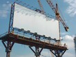 © Ratchadaporn - Blank Billboard on Construction Site with Cranes and Workers against Cloudy Sky