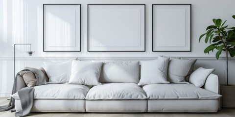 Wall Mural - A white couch with three empty frames on the wall. The couch is the main focus of the image