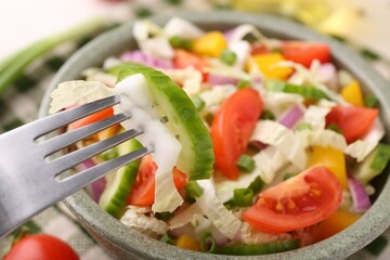 Eating delicious salad with Chinese cabbage at table, closeup