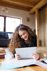 Wall Mural - A beautiful university student is writing her thesis on a laptop, sitting at home on the couch.