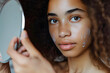 © Evan - A volunteer holding a mirror and observing the effects of a skincare treatment on their face