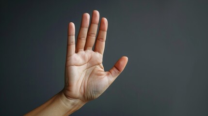 Stopping hand gesture with an open palm on a dark gray scene	