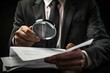 © Fotograf - A person wearing a suit holds a magnifying glass, suggesting investigation or detection