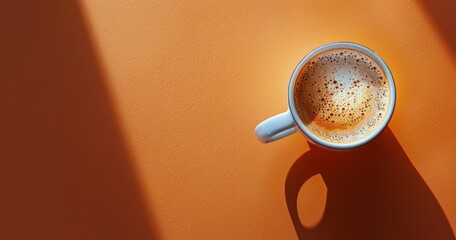 Top View of a Cup of Coffee With Cinnamon Sprinkles on an Orange Background