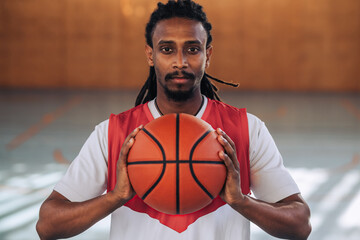 Wall Mural - Portrait of an arabic black man basketball player holding a ball with both hands