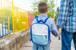 © Dragana Gordic - First day at school. father leads a little child school boy in first grade. Parent and pupil of primary school go hand in hand. Man and boy with backpack behind the back. Beginning of lessons.