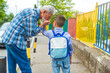 © Dragana Gordic - First day at school. father leads a little child school boy in first grade. Parent and pupil of primary school go hand in hand. Man and boy with backpack behind the back. Beginning of lessons.