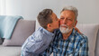 © Dragana Gordic - Beautiful little boy kissing happily his grandfather. Child kiss grandfather. Great grandfather taking care of grandchild while sitting on couch.