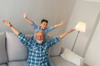 © Dragana Gordic - Laughing grandfather with his grandson as they play together indoors in the living room with the cute young boy hugging him from behind. Mature man playing with grandson at home.