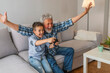 © Dragana Gordic - Grandfather and grandson playing video game with console, happy time together. Grandfather with his nephew seated on a sofa playing video games. Grandfather and child playing game console