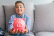 © Dragana Gordic - Portrait of cute little boy with piggy bank. Little boy saving money in piggy bank. Little Boy Kid Adorable Cute Piggy Bank Saving Portrait Concept. Little boy saving coins in piggy bank at home