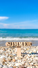 Wall Mural - Wooden summer sign on the beautiful rocky beach