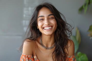 Happy woman, long dark hair, in orange top, necklace