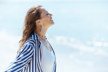 Wall Mural - smiling stylish woman on beach enjoying peace of mind