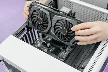 system administrator installing graphics card into system unit, assembling PC of different accessories or components, close-up view of hands, computer repair and maintenance concept