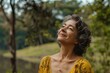 © evgenia_lo - Senior Hispanic woman in a yellow dress enjoying nature