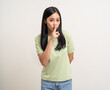 © Chanakon - Happy beautiful young asian woman whispering some secret gossip. Excited pretty latin girl index finger on mouth standing pose on isolated white background.