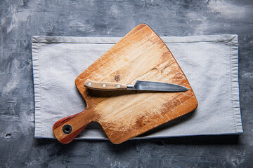 Wall Mural - old cutting board with a knife and a napkin ongrey wooden table. View from above. copyspace.