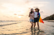 © Chanakon - Young couple asian lesbian with pride movement LGBT holding rainbow flag for freedom. Demonstrate rights LGBTQ celebration pride Month lesbian Pride Symbol. Walking on the sand sea beach with sunset