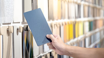 Wall Mural - Designer hand picking samples board from material swatch wall display in material library. Choosing glossy laminate texture in gray tone collection for interior architecture or furniture design