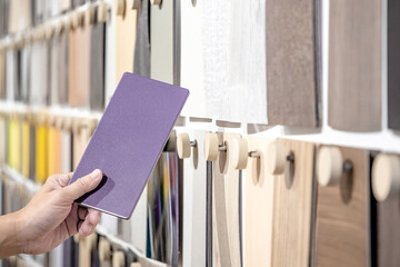 Wall Mural - Designer hand picking samples board from material swatch wall display in material library. Choosing glossy laminate texture in purple tone collection for interior architecture or furniture design
