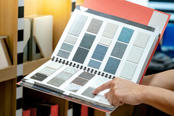 Wall Mural - designer hand pointing at sample stone material texture on furniture finishing catalog in material l